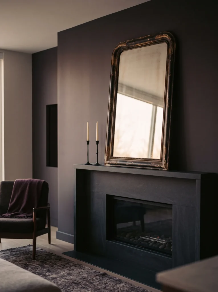 Oversized foxed antique mirror above a mantel with brass sconces