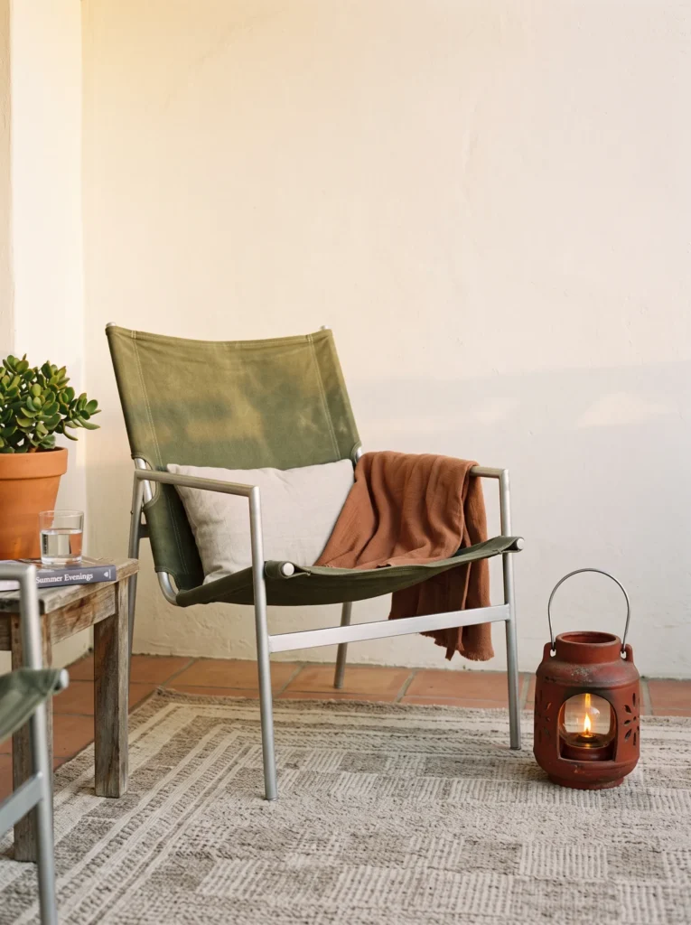 Olive canvas sling chair beside a rust-red citronella lantern