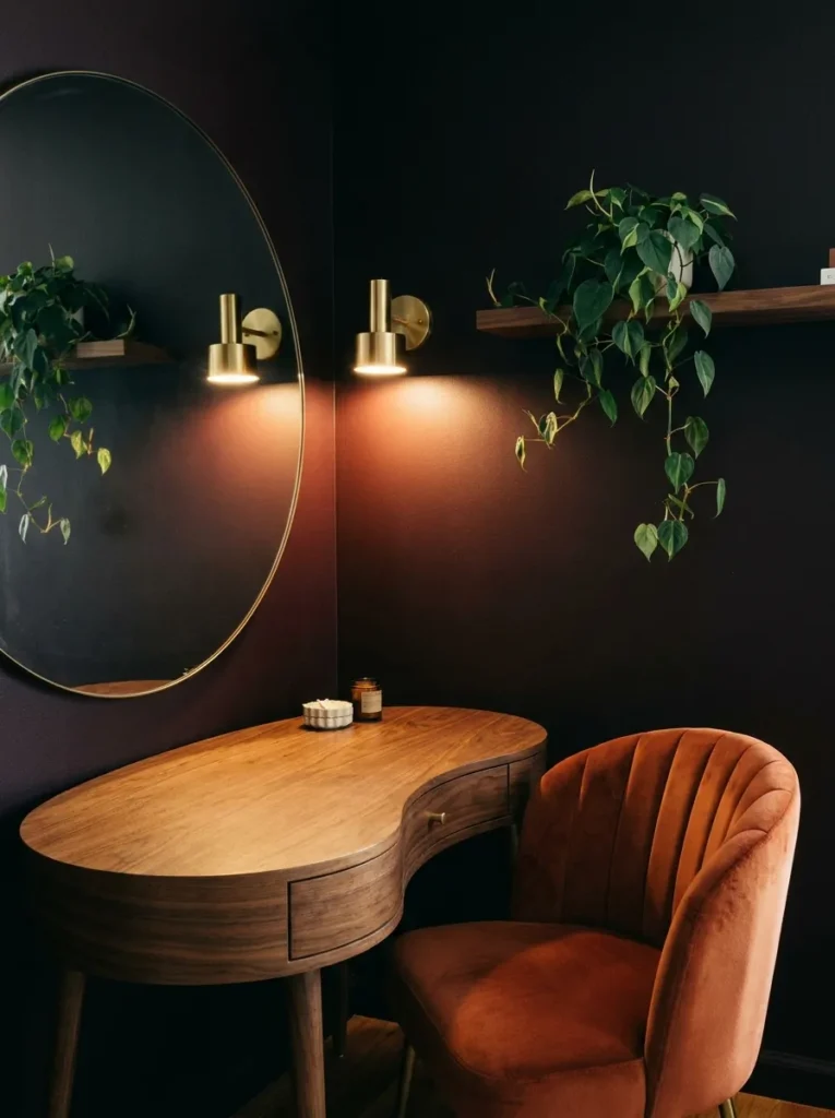  Curved walnut kidney desk against a black cherry wall with a mirror reflecting brass sconce light