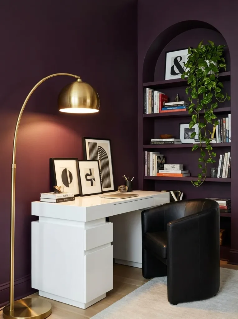 White lacquer pedestal desk against a deep plum wall with an arched brass floor lamp