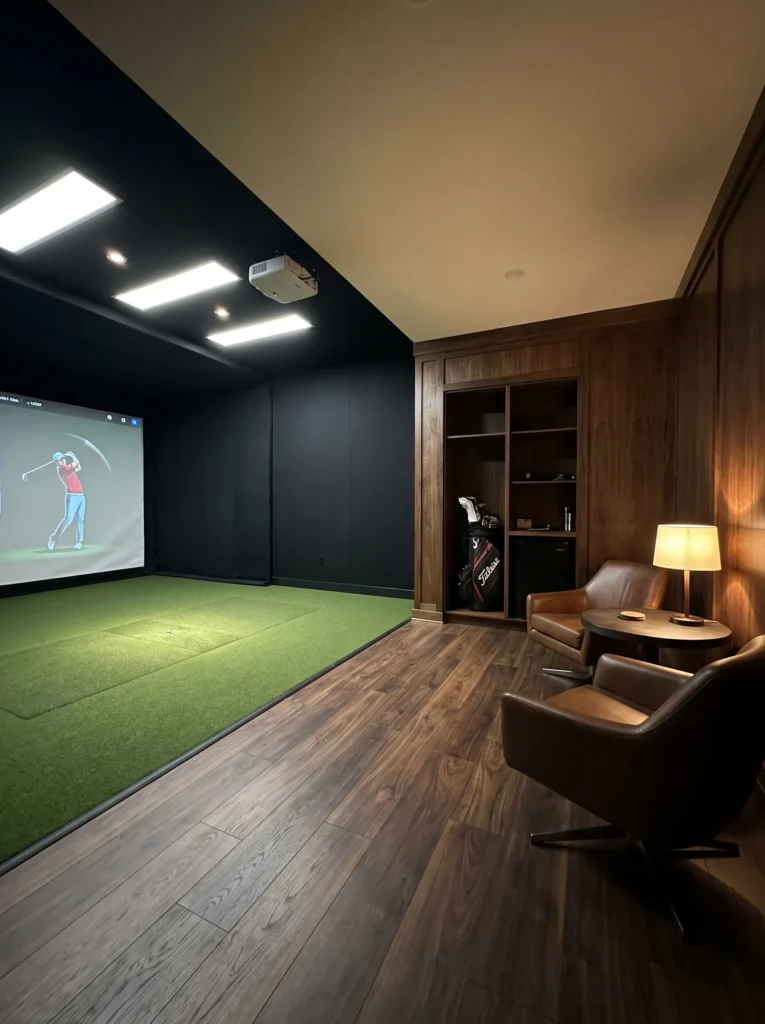 Golf simulator lounge with matte black hitting bay and walnut seating corner"
