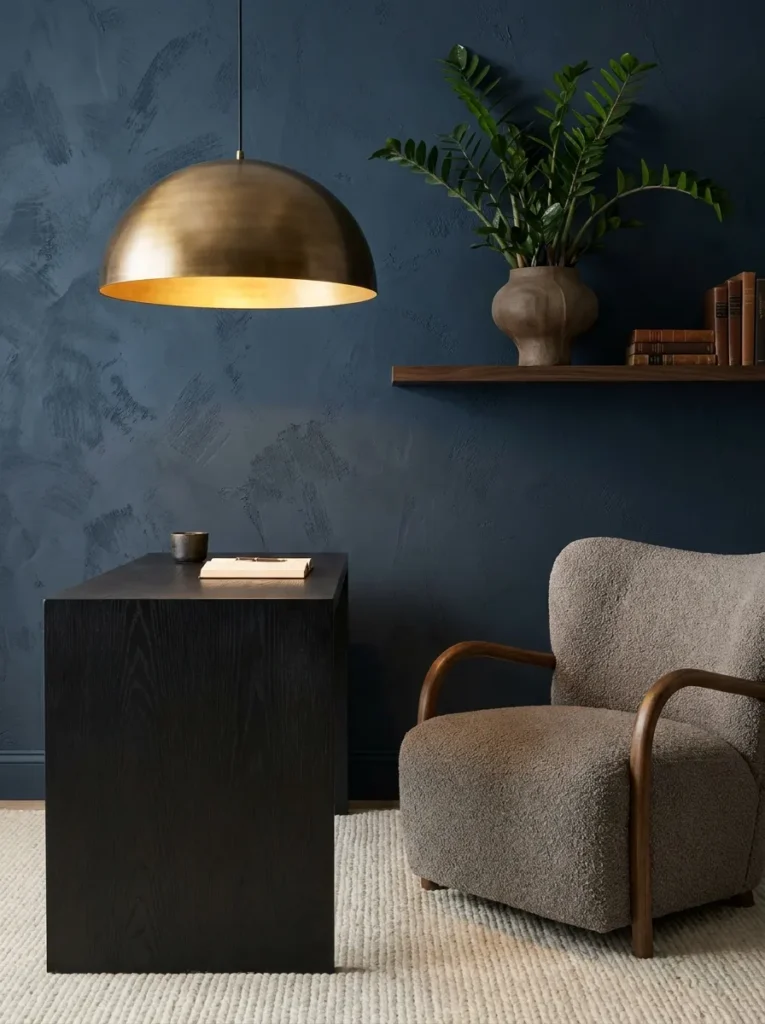 Textured midnight blue limewash wall behind a black oak desk with a low brass dome pendant