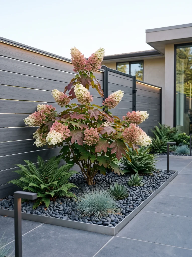White mophead hydrangeas flanking a stone walkway with warm low-voltage uplighting at dusk.