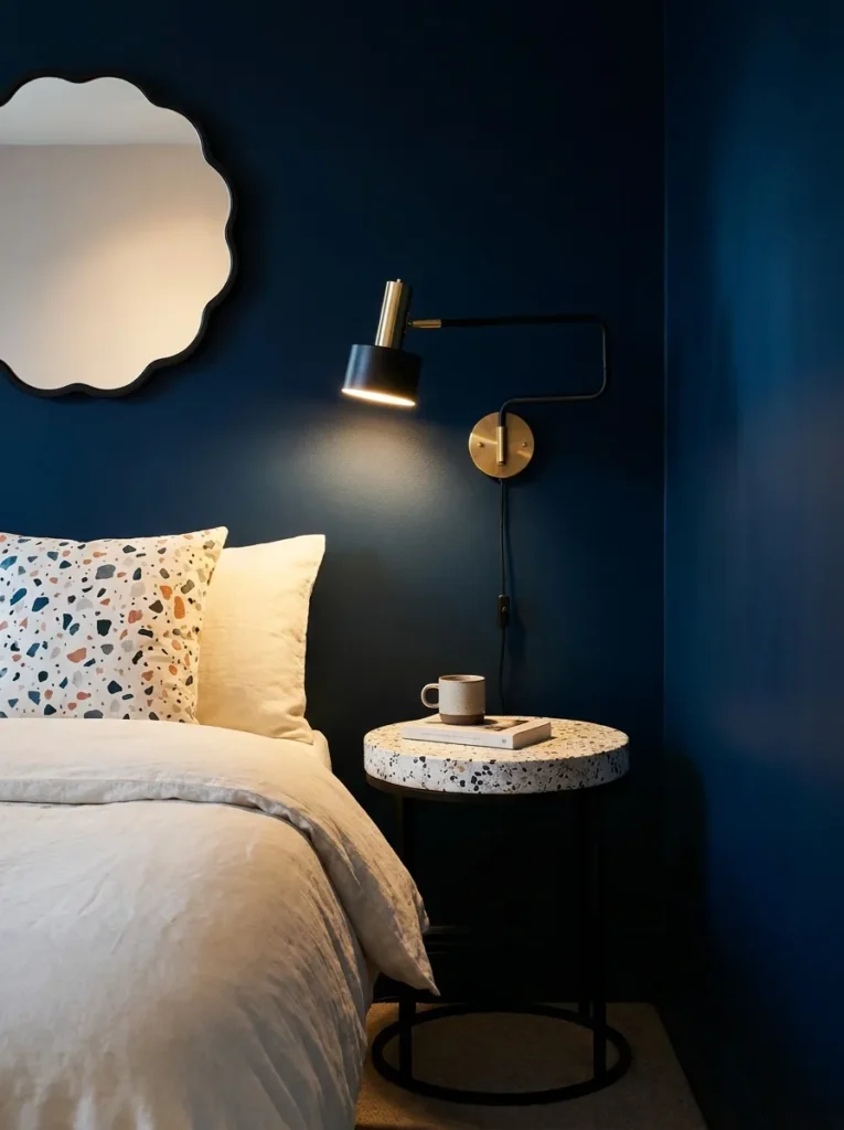 Round terrazzo-topped nightstand with an articulated lamp against ink-black walls
