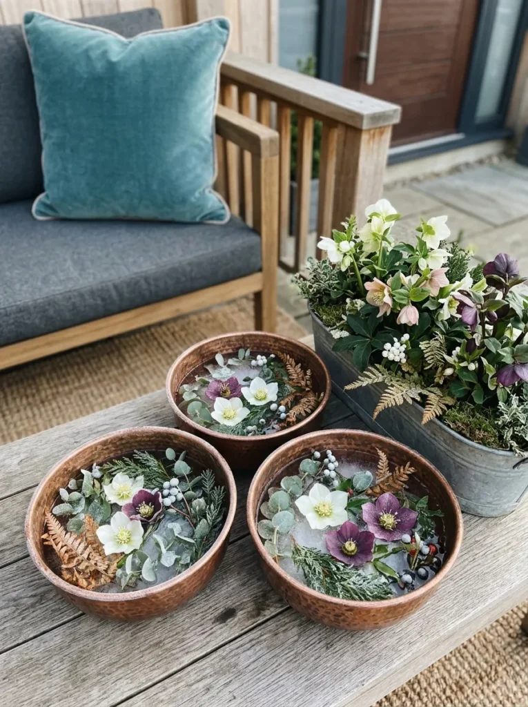 Hammered copper bowls with frozen greenery beside teal velvet cushions and hellebore blooms