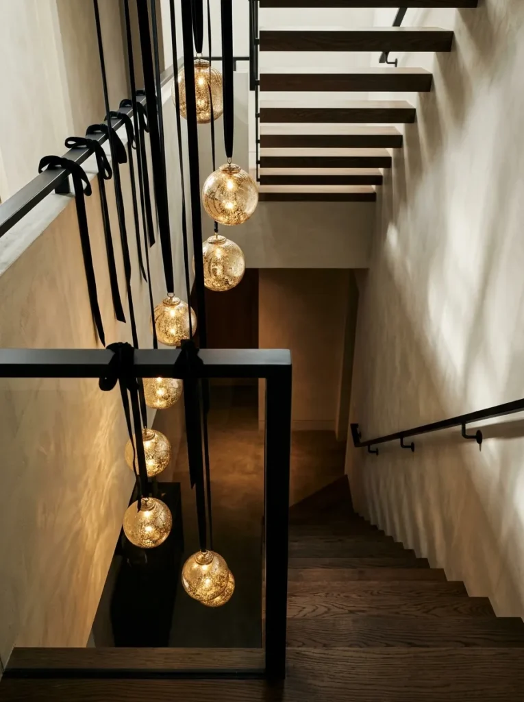 "Champagne gold orbs hanging from a staircase rail on black ribbon"